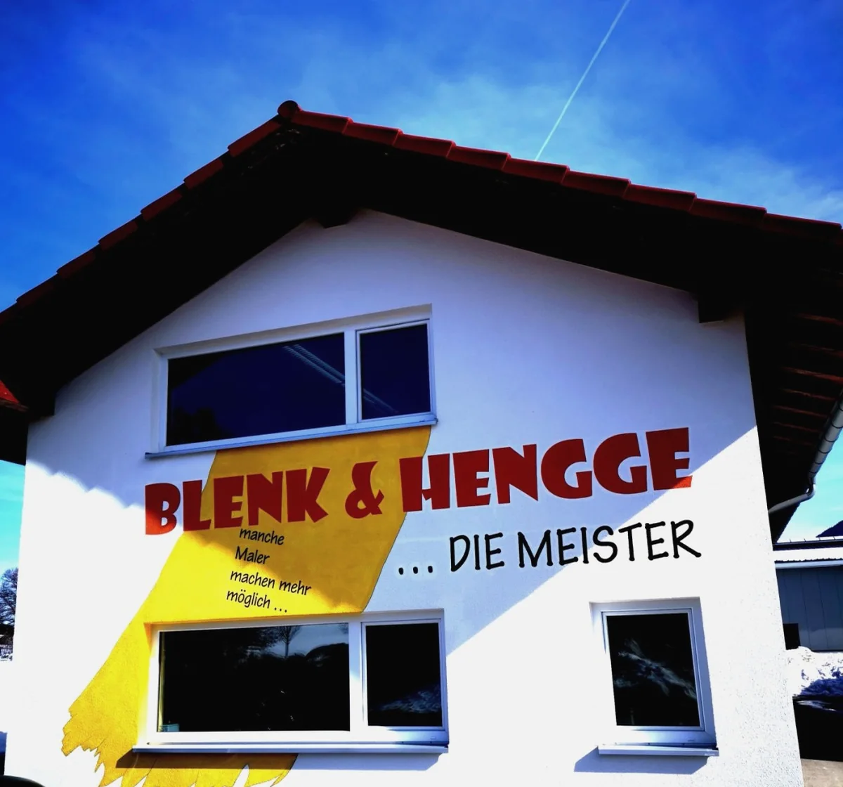 Hausfassade mit dem gelben Pinselstrich und dem Logo von Blenk und Hengge